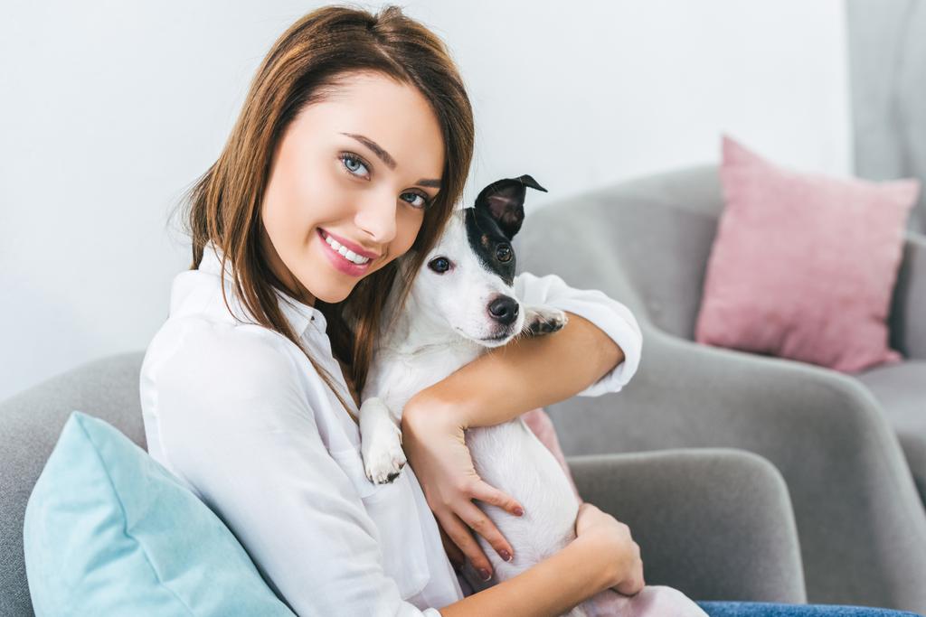χαμογελαστή γυναίκα με Τζακ Ράσελ τεριέ σκύλο που κάθεται στον καναπέ στο σπίτι - Φωτογραφία, εικόνα