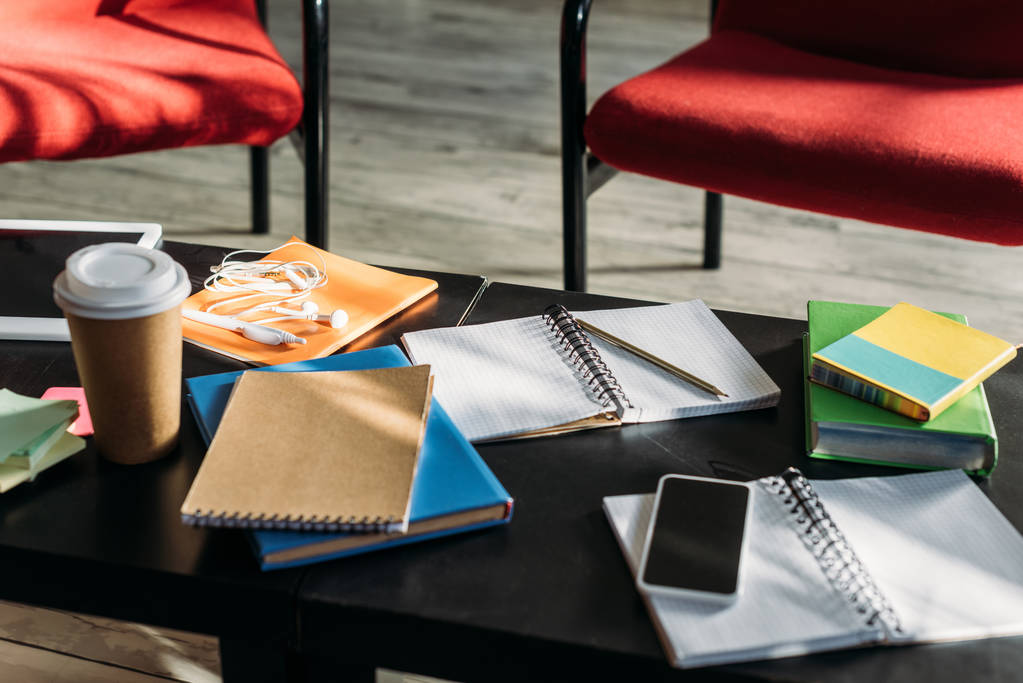 Smartphone, Notebooks und Einweg-Kaffeetasse auf dem Tisch - Foto, Bild