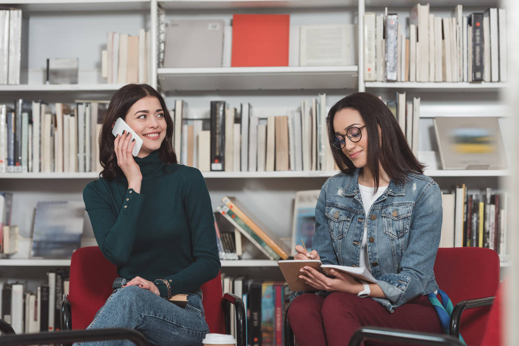 estudante atraente falando por smartphone na biblioteca
 - Foto, Imagem