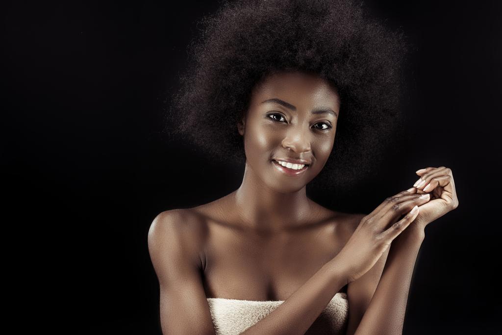 aantrekkelijke african american vrouw bedekt met handdoek geïsoleerd op zwart - Foto, afbeelding