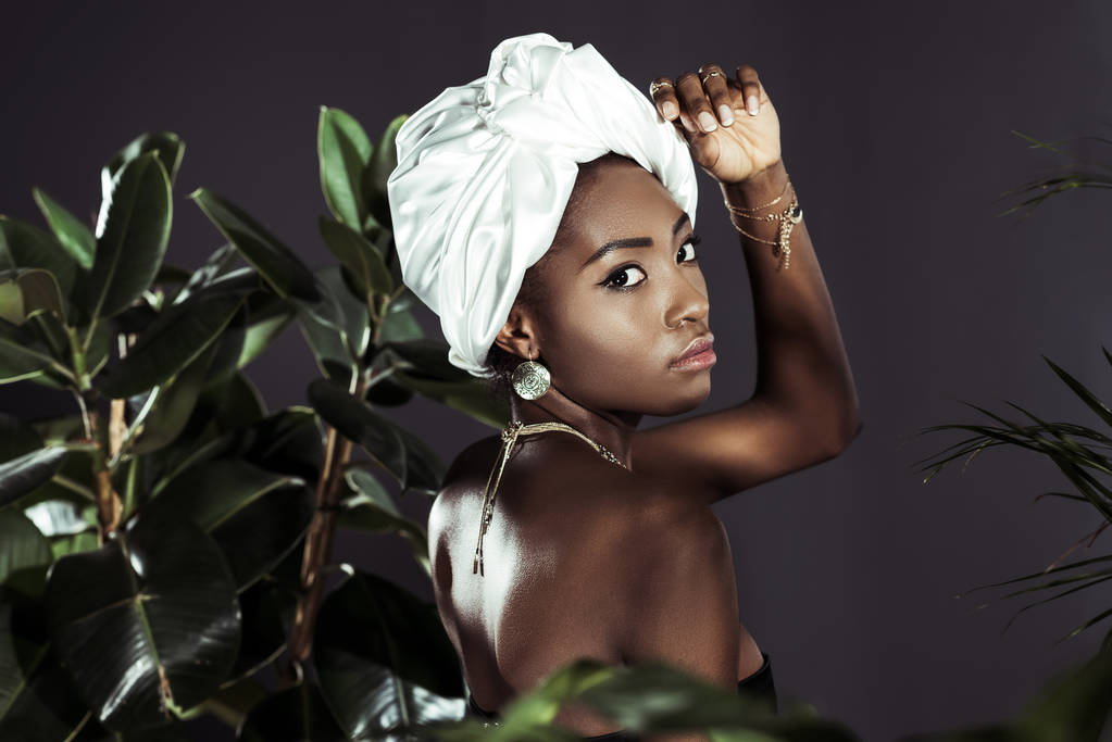 sensual afroamericana mujer en alambre cabeza abrigo detrás de hojas
 - Foto, Imagen