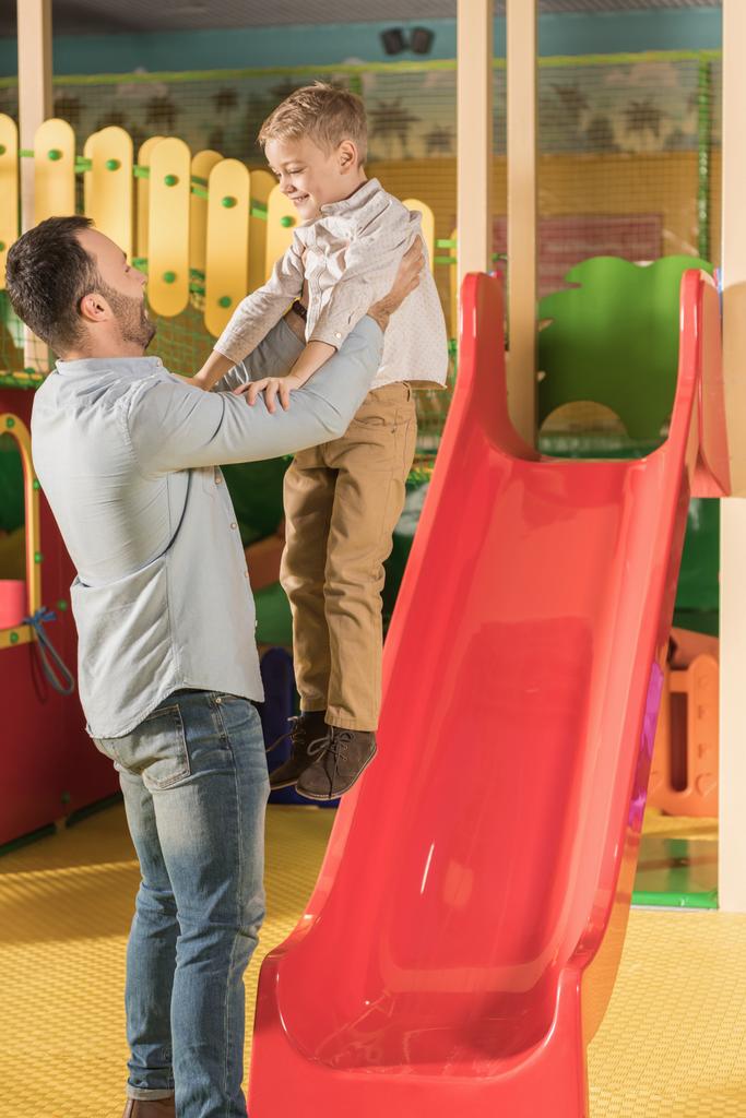 щасливий батько носить маленького сина в розважальному центрі
 - Фото, зображення