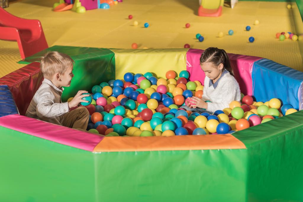 милые маленькие дети играют в бассейне с красочными шариками
 - Фото, изображение
