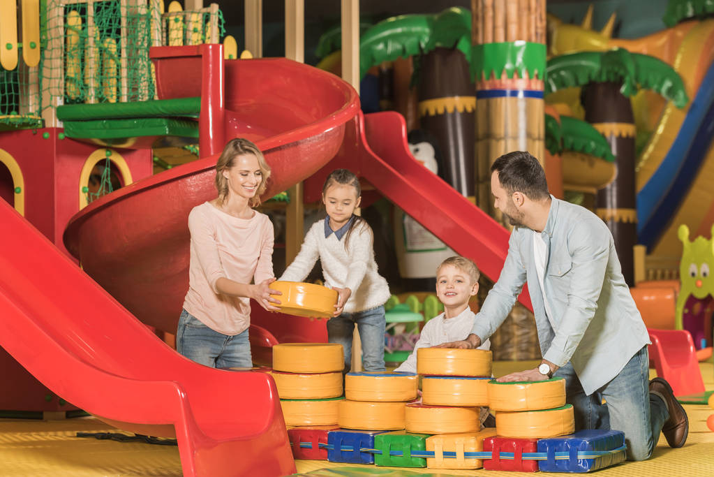 šťastní rodiče s rozkošný malý děti hrají společně v herním centru - Fotografie, Obrázek