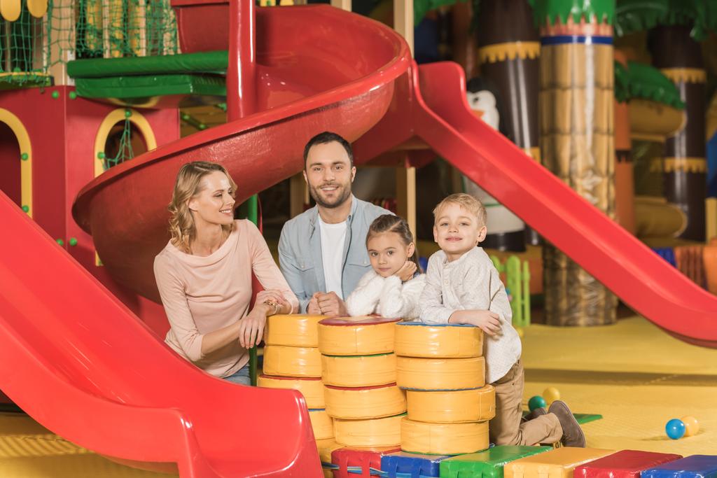 familia feliz con dos niños sonriendo a la cámara mientras juegan juntos en el centro de entretenimiento
  - Foto, Imagen