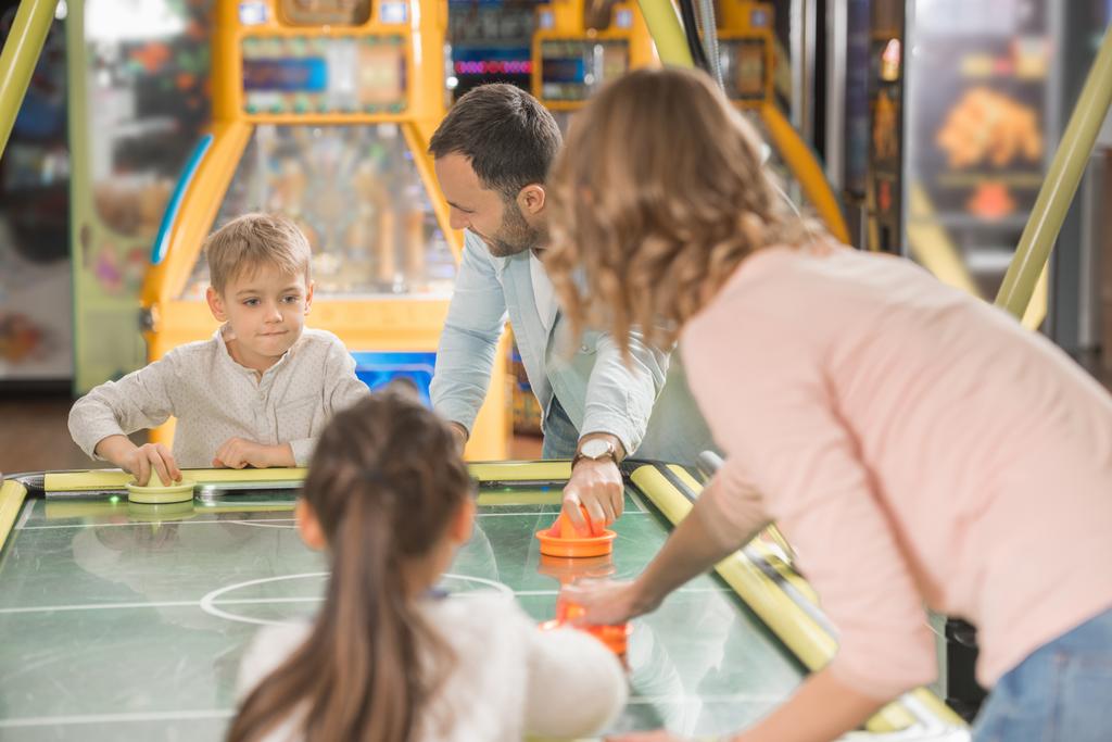 happy family with two children playing air hockey together in game center - Photo, Image