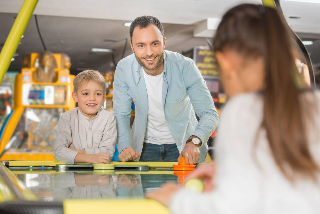 happy father with adorable little kids playing air hockey in entertainment center - Photo, Image