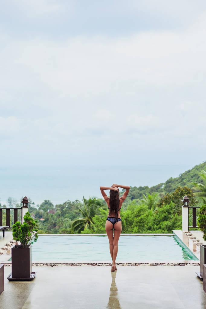 visão traseira da menina posando na piscina no resort tropical
 - Foto, Imagem