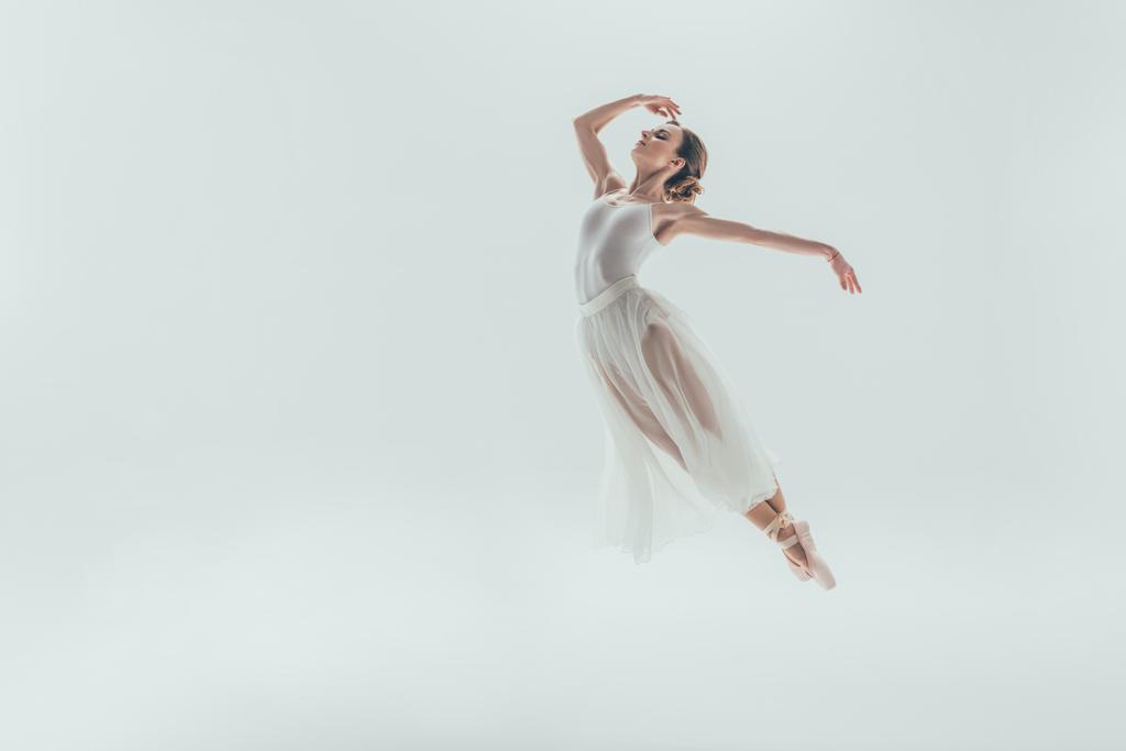 Elegante Balletttänzerin im weißen Kleid springt im Studio, isoliert auf Weiß - Foto, Bild