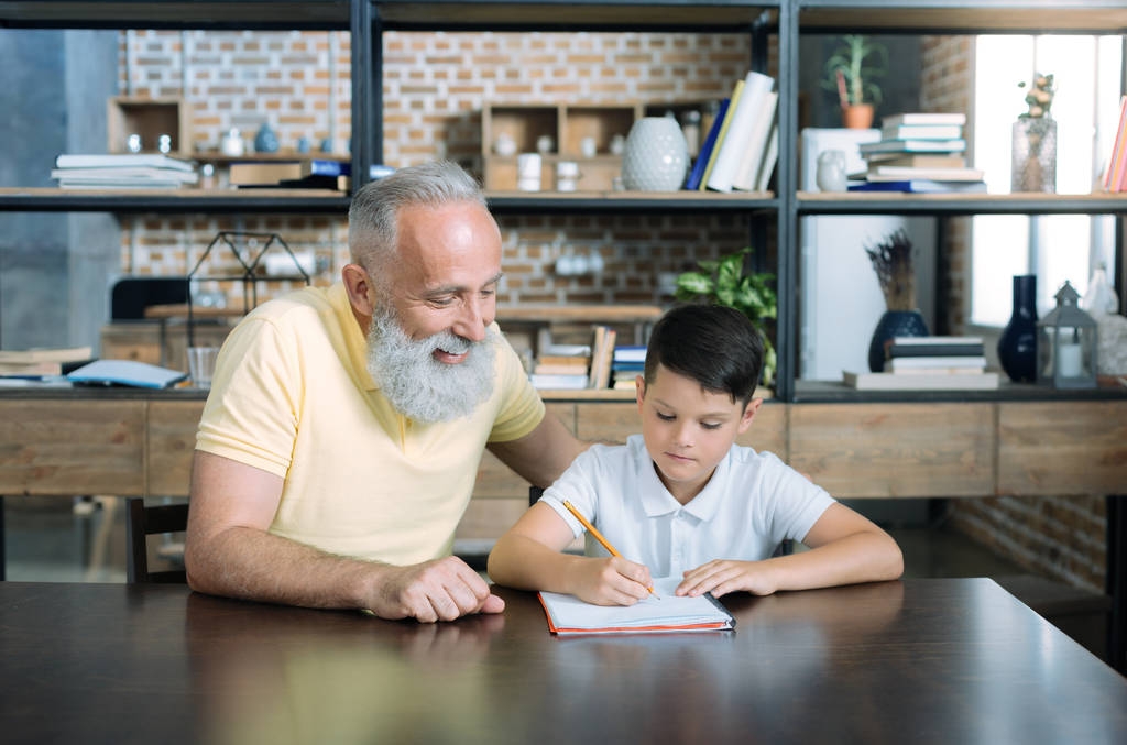 Estremamente felice uomo anziano guardando nipote facendo i compiti
 - Foto, immagini