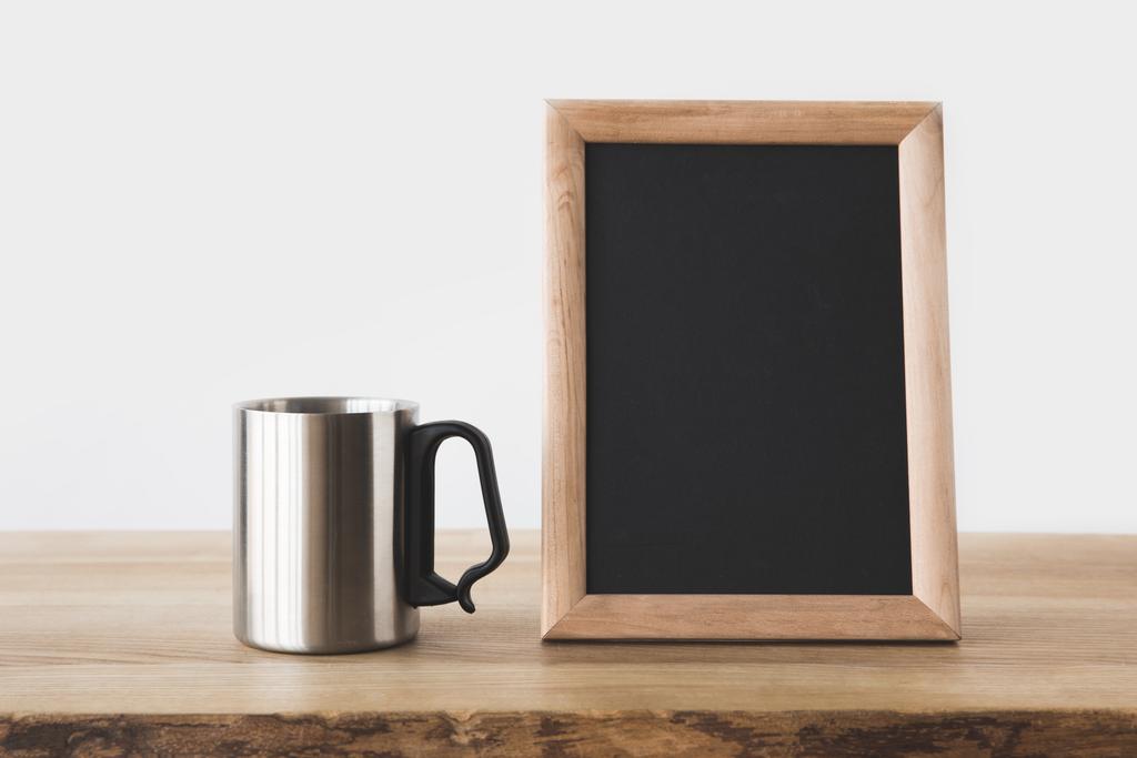 Zilveren beker en schoolbord in frame op houten tafel op wit  - Foto, afbeelding