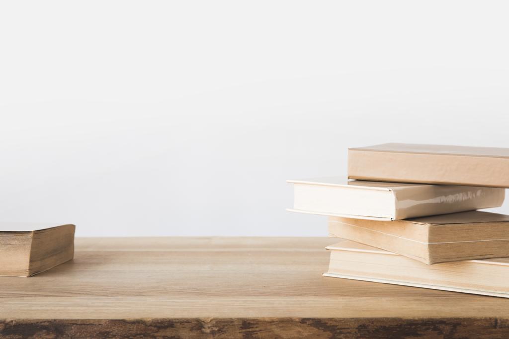 стопка старых книг на деревянном столе на белом
  - Фото, изображение