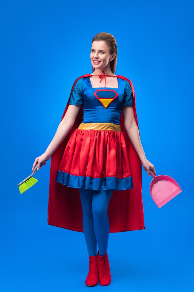 Kobieta w strój superbohatera z miotły i szufelka do czyszczenia, na niebieskim tle - Zdjęcie, obraz