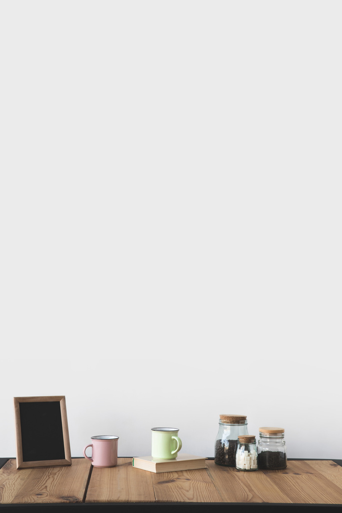 白の木製テーブルの上のコーヒー カップとフレームで空の黒板  - 写真・画像