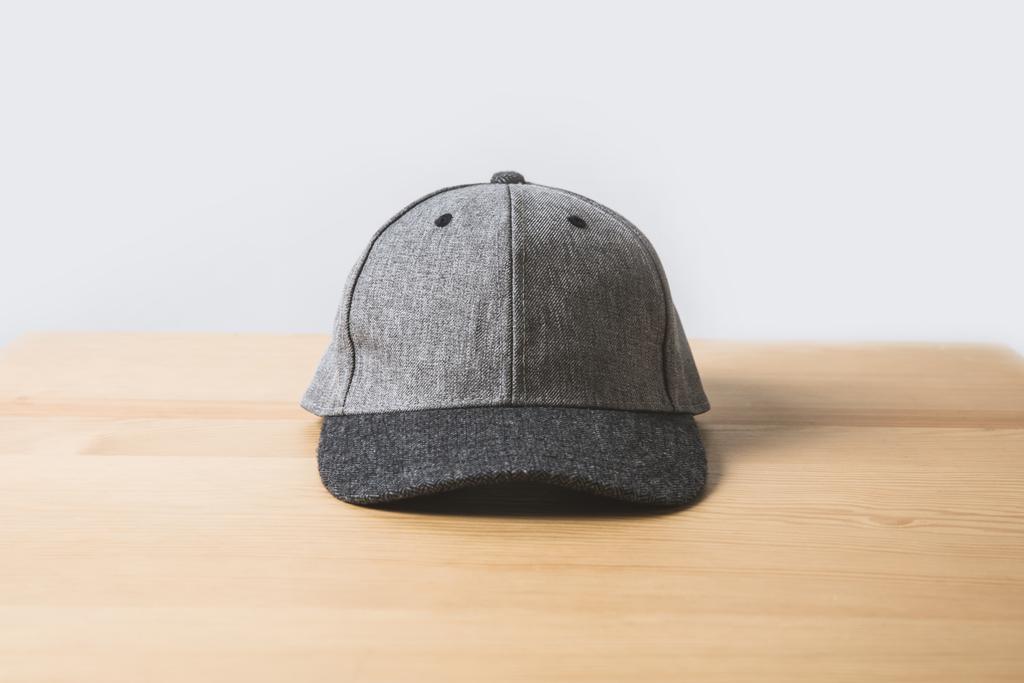 eine graue Mütze auf Holztisch auf weiß  - Foto, Bild