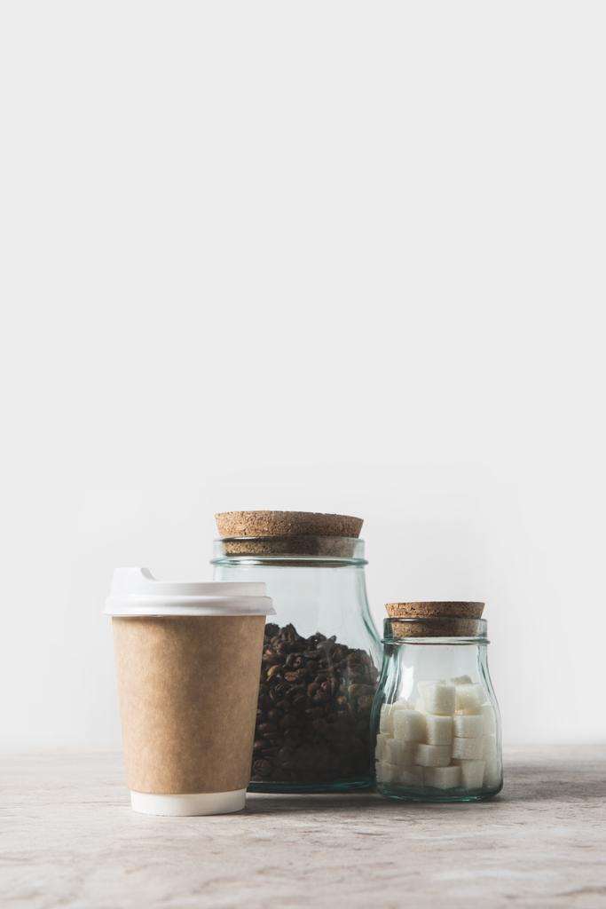 grains de café, sucre raffiné et tasse à café jetable sur table en marbre blanc
  - Photo, image