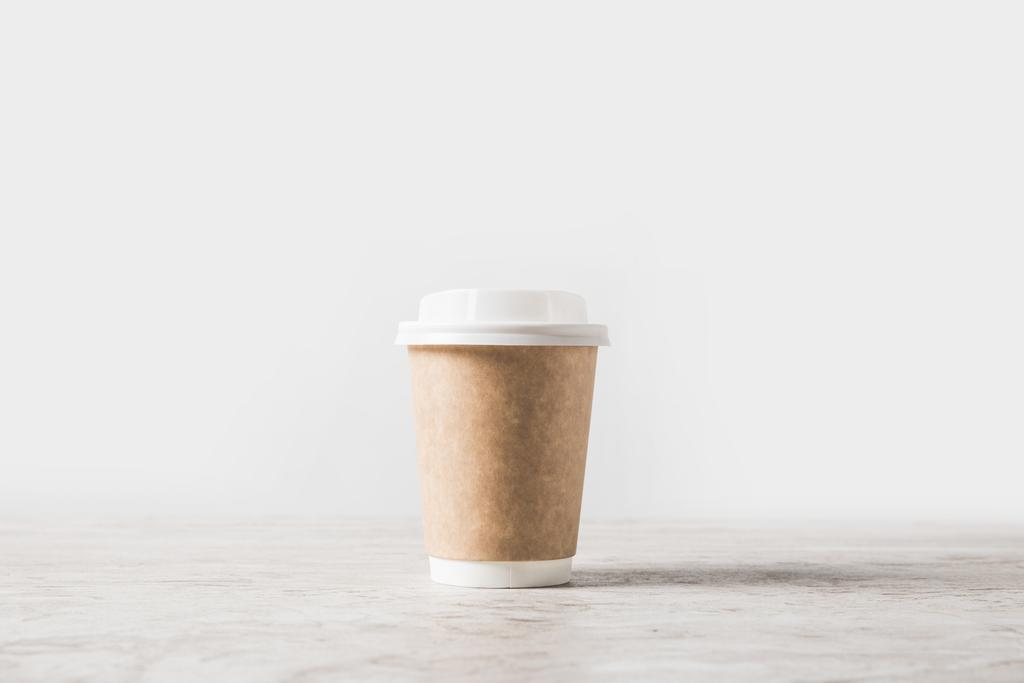 een wegwerp koffiekopje op marmeren tafel op wit  - Foto, afbeelding