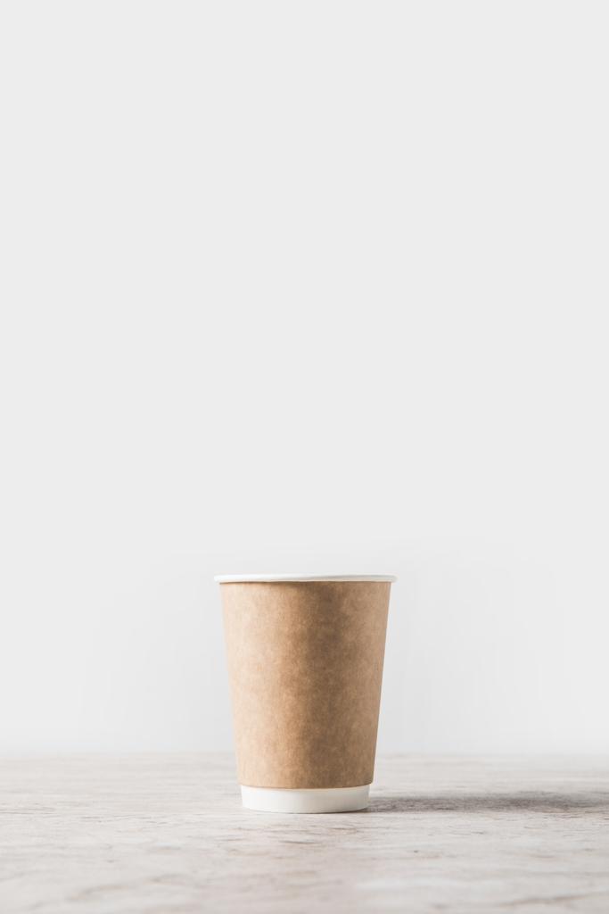 Kertakäyttöinen kahvikuppi marmoripöydällä valkoisella
  - Valokuva, kuva