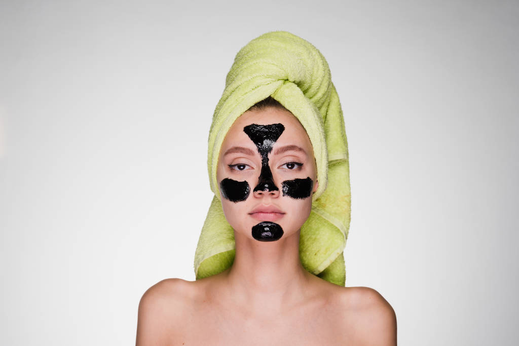 彼女の頭の上のタオルを持つ女性は、問題領域に彼女の顔にクレンジング マスクを適用 - 写真・画像