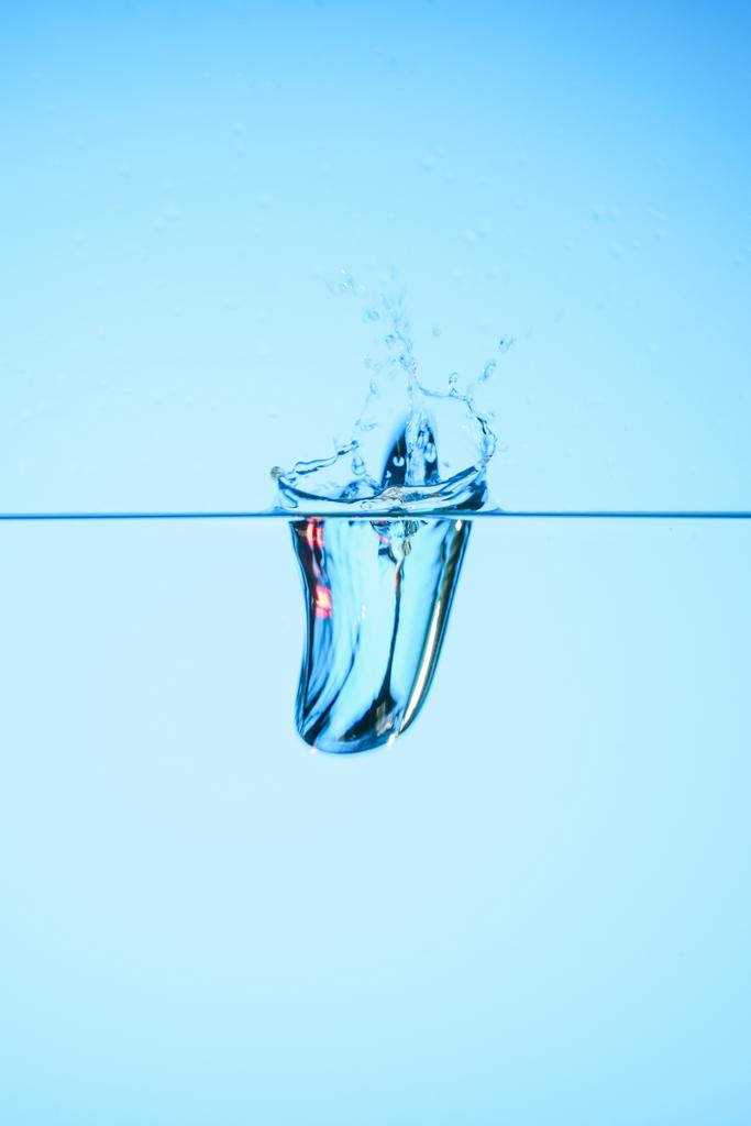 reines Wasser mit Spritzwasser, isoliert auf blau - Foto, Bild