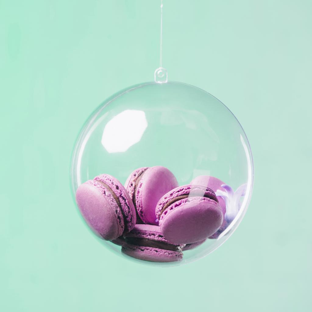 macarons ve skleněné kouli visící na tyrkysové pozadí - Fotografie, Obrázek