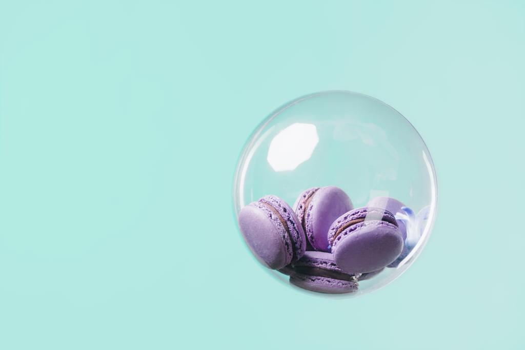 tasty purple macarons in glass ball floating on turquoise background - Photo, Image