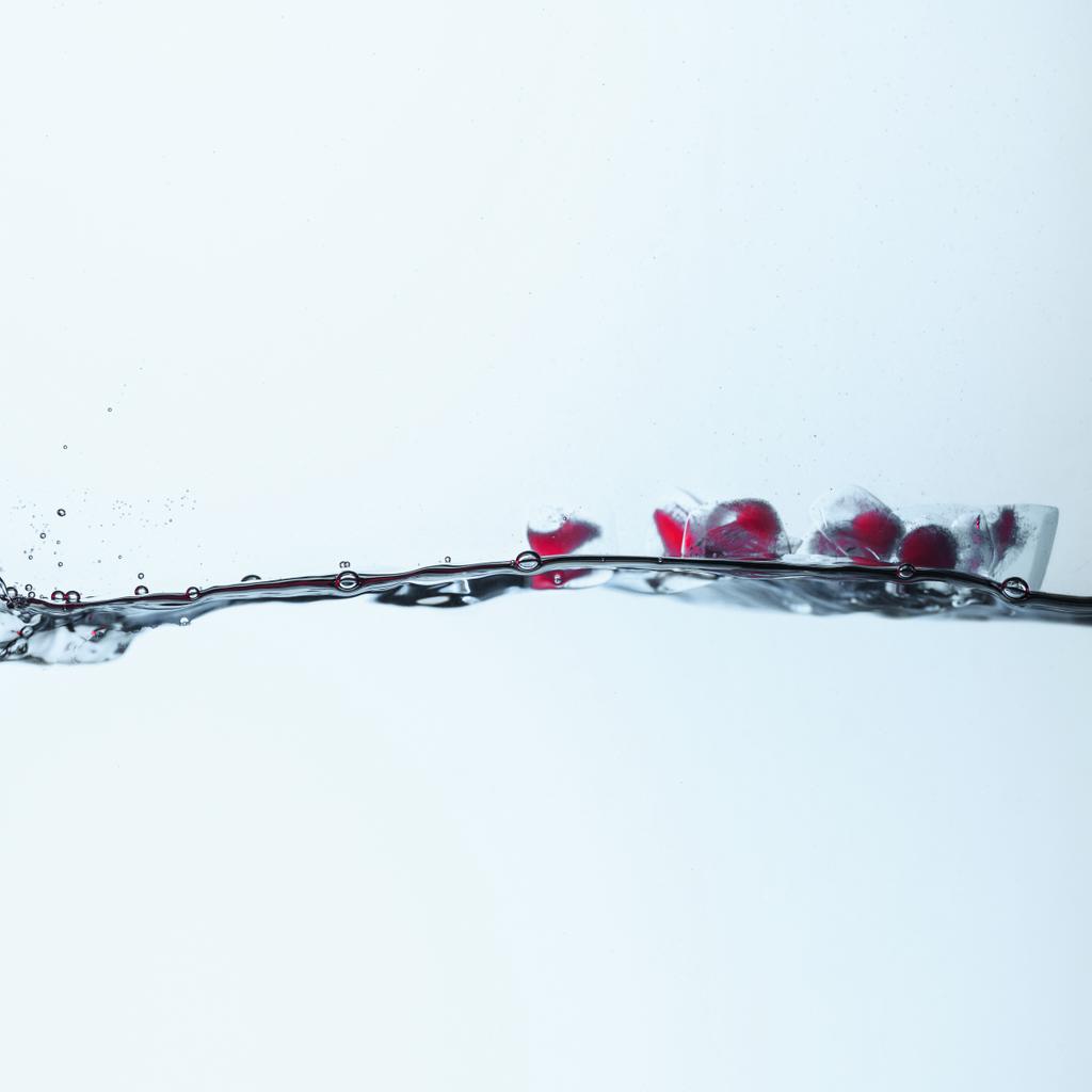 cubitos de hielo con bayas rojas que se derriten en agua, aislados en blanco
 - Foto, Imagen
