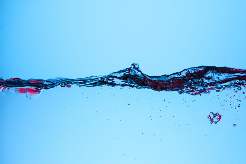 ice cubes with berries in flowing water, isolated on blue - Photo, Image