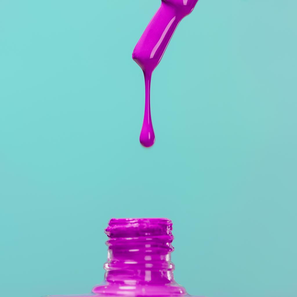 nail polish pouring down into bottle isolated on blue - Photo, Image