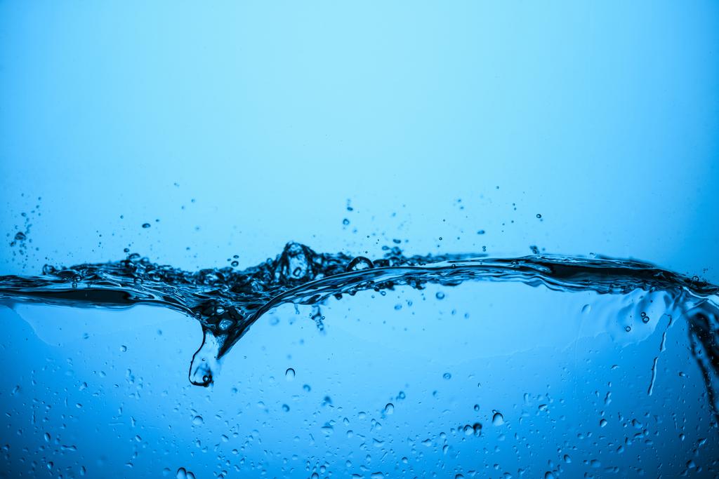 salpicando água com bolhas, isolado em azul
 - Foto, Imagem