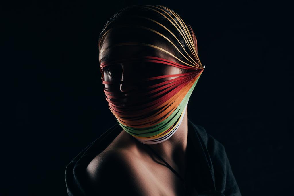 жінка з кольоровим креслярським папером на голові дивиться ізольовано на чорному
 - Фото, зображення