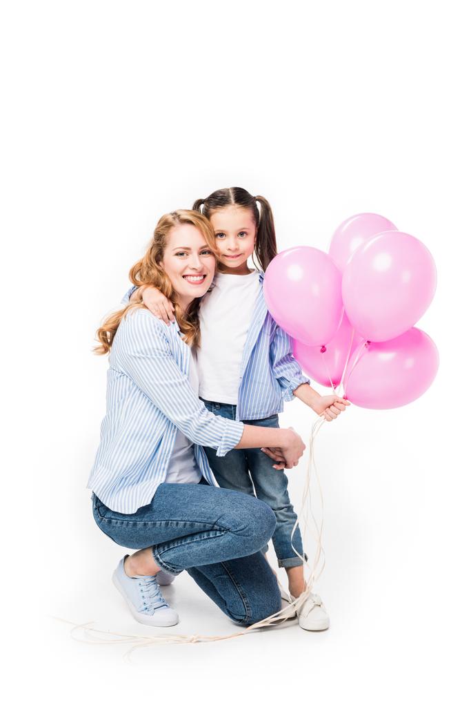 smiling mother and daughter with pink balloons hugging each other isolated on white - Photo, Image