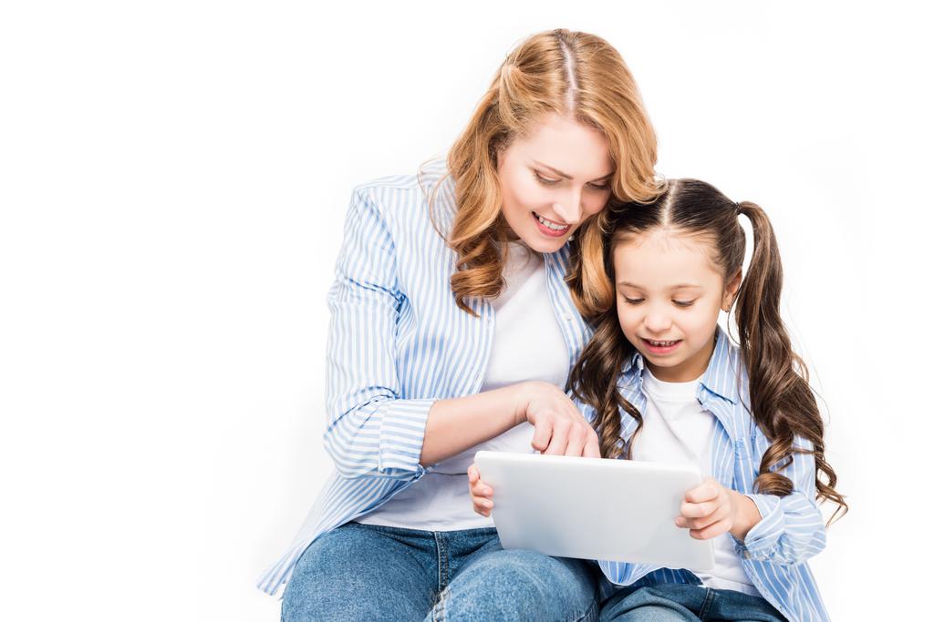 Portret van de moeder en dochter met behulp van Tablet PC samen op wit wordt geïsoleerd - Foto, afbeelding