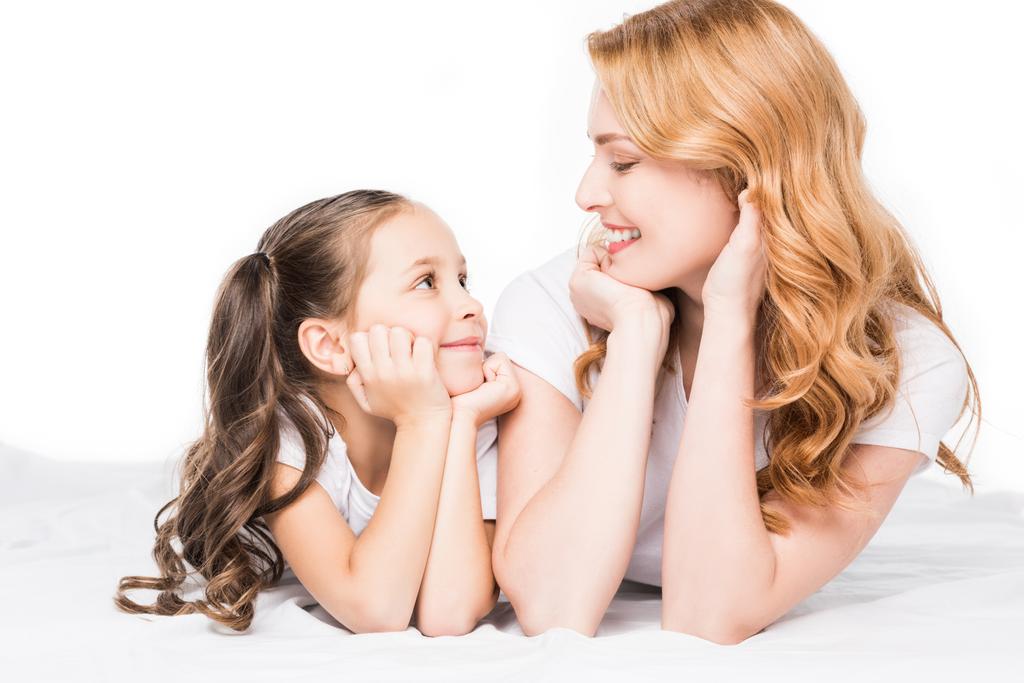 портрет улыбающейся матери и дочери, смотрящих друг на друга изолированно на белом
 - Фото, изображение