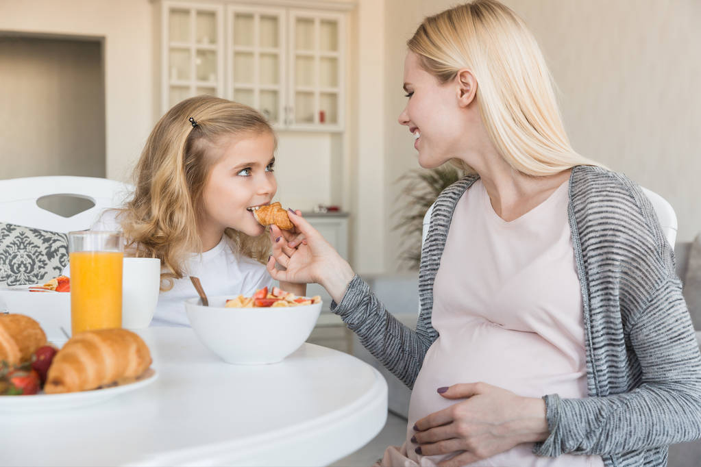 várandós anya lánya harapni croissant-t ad - Fotó, kép