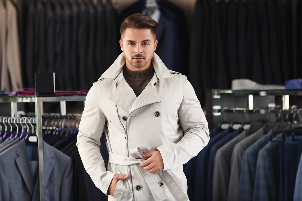 Nuori mies tyylikkäässä takissa miesten vaatekaupassa
 - Valokuva, kuva