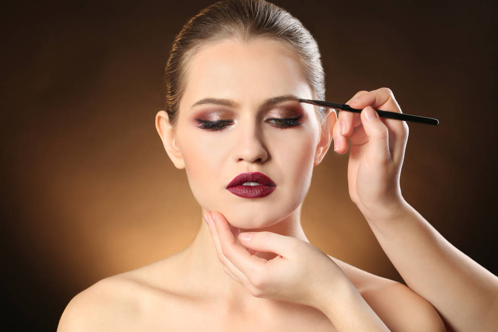 暗い背景に女性の顔に化粧を適用するプロ顔アーティスト - 写真・画像