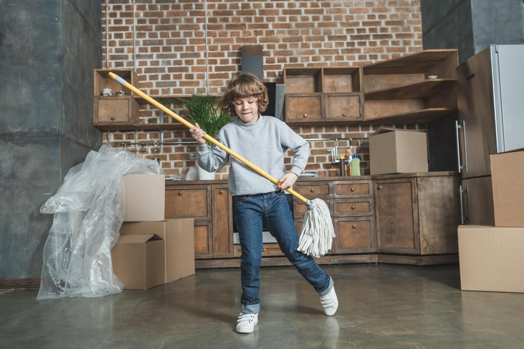 roztomilý šťastný chlapeček hraje s mopem v novém bytě  - Fotografie, Obrázek