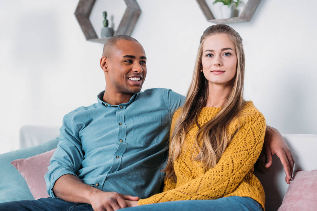 multicultural couple holding hands on sofa - Photo, Image
