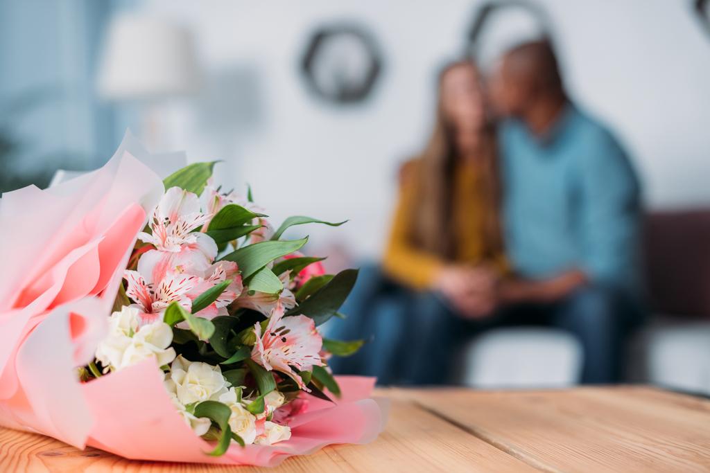 multicultural couple kissing with bouquet on foreground - Photo, Image