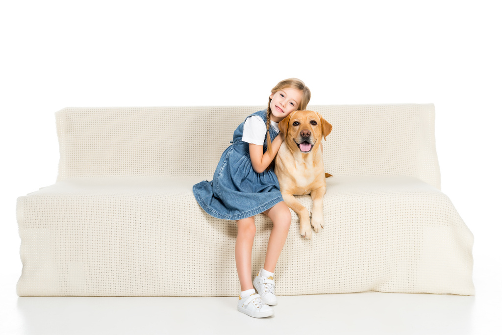 usmívající se dítě a pes sedí na pohovce, izolované na bílém - Fotografie, Obrázek