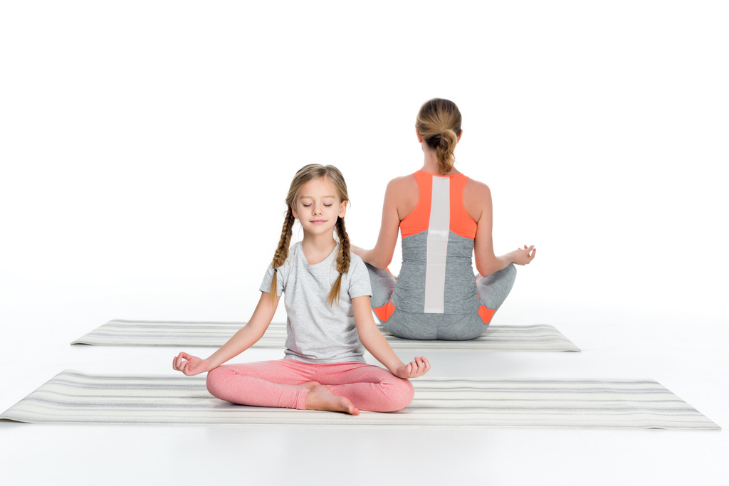 athletische Mutter und Tochter praktizieren Yoga auf Matten zusammen isoliert auf weiß - Foto, Bild