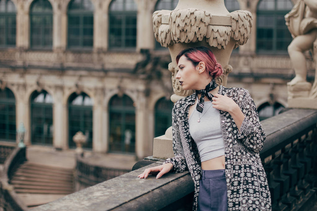 красивая задумчивая молодая женщина смотрит в сторону, стоя возле дворца барокко в Дрездене, Германия
  - Фото, изображение
