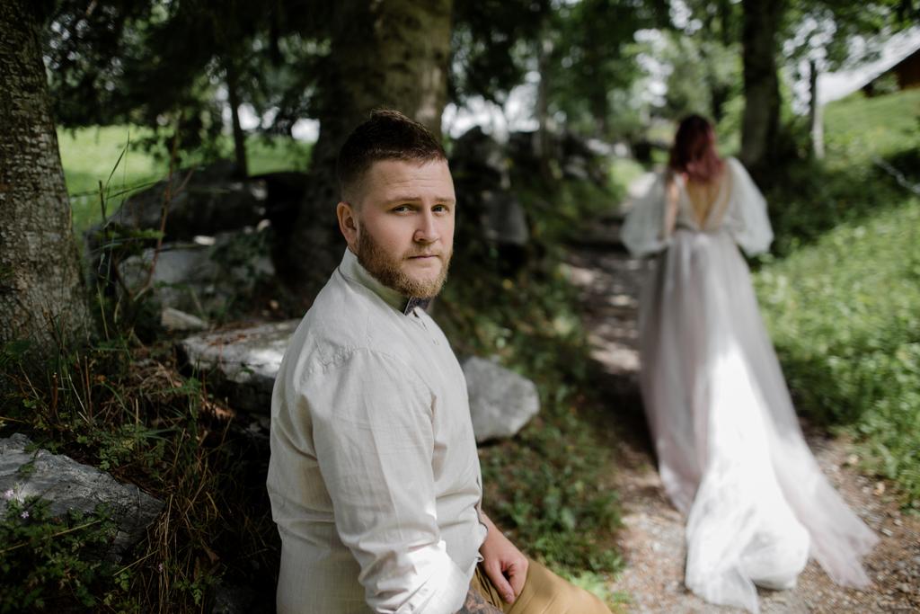 カメラとアルプスの山道を歩く花嫁を見てハンサムな若い新郎 - 写真・画像
