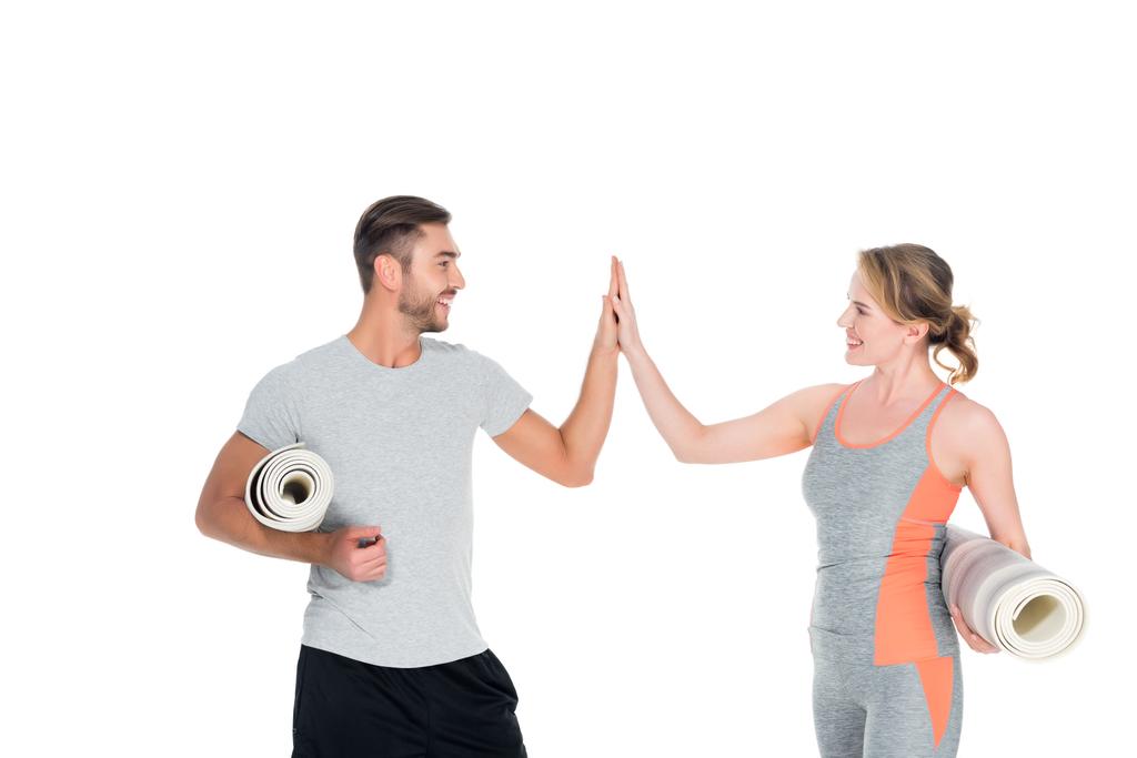 pareja atlética con colchonetas de yoga dando cinco a cada uno aislado en blanco
 - Foto, imagen