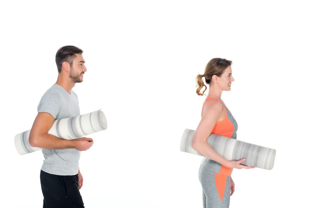 vista lateral de pareja atlética con colchonetas de yoga aisladas en blanco
 - Foto, imagen