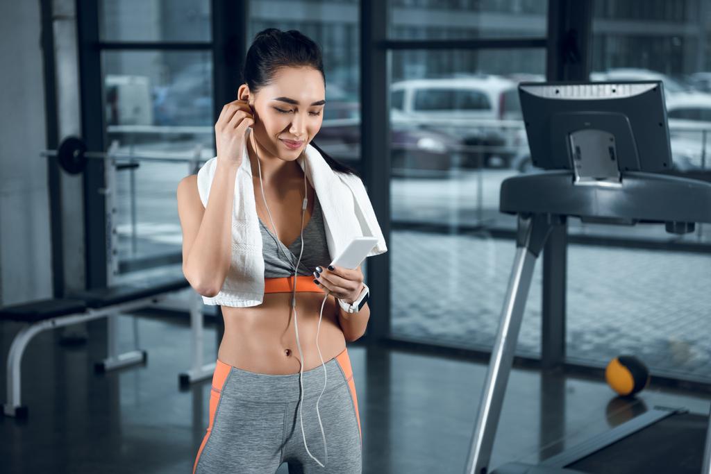 young athletic woman listening music with earphones at gym - Photo, Image
