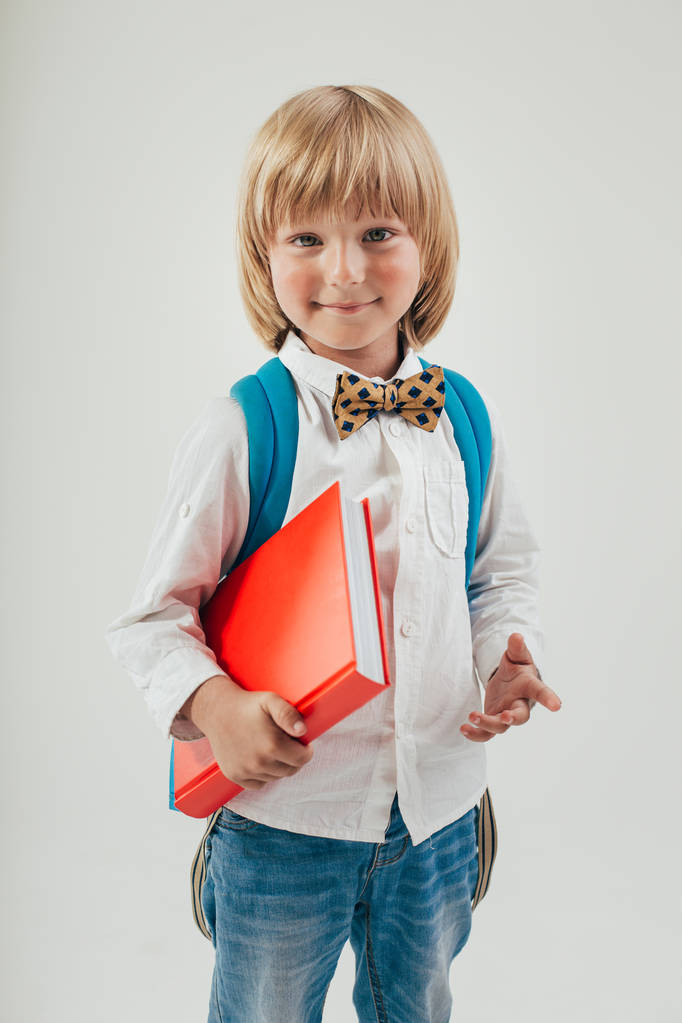 Портрет счастливого школьника с книгами и яблоком на белом фоне. Образование изолированное. Школьный детский сад
 - Фото, изображение