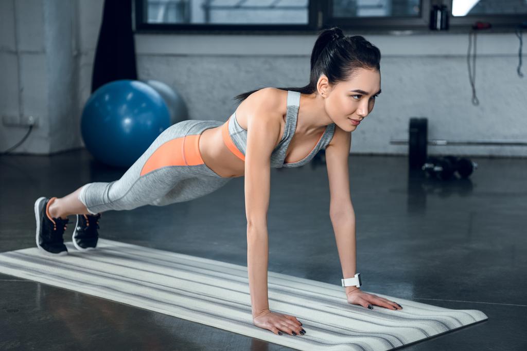 молодая спортсменка делает доску на коврике для йоги в спортзале
 - Фото, изображение
