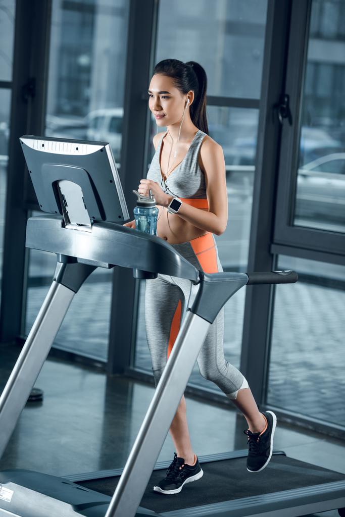 young attractive sportswoman jogging on treadmill at gym - Photo, Image